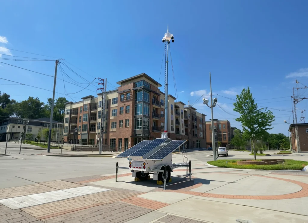 Mobile surveillance unit with solar panels and cameras near modern residential buildings