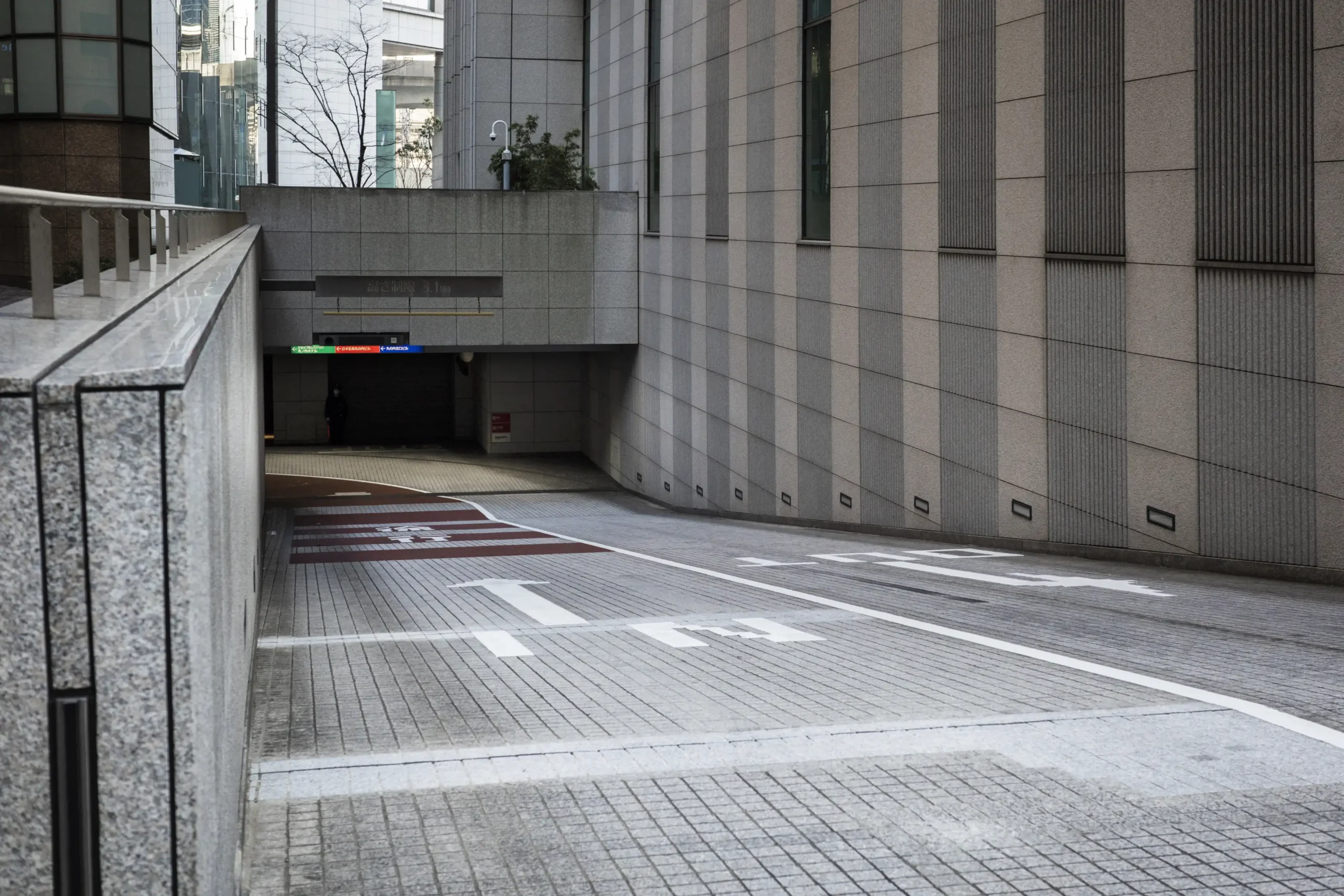 Urban driveway leading to underground garage with directional arrows and signage
