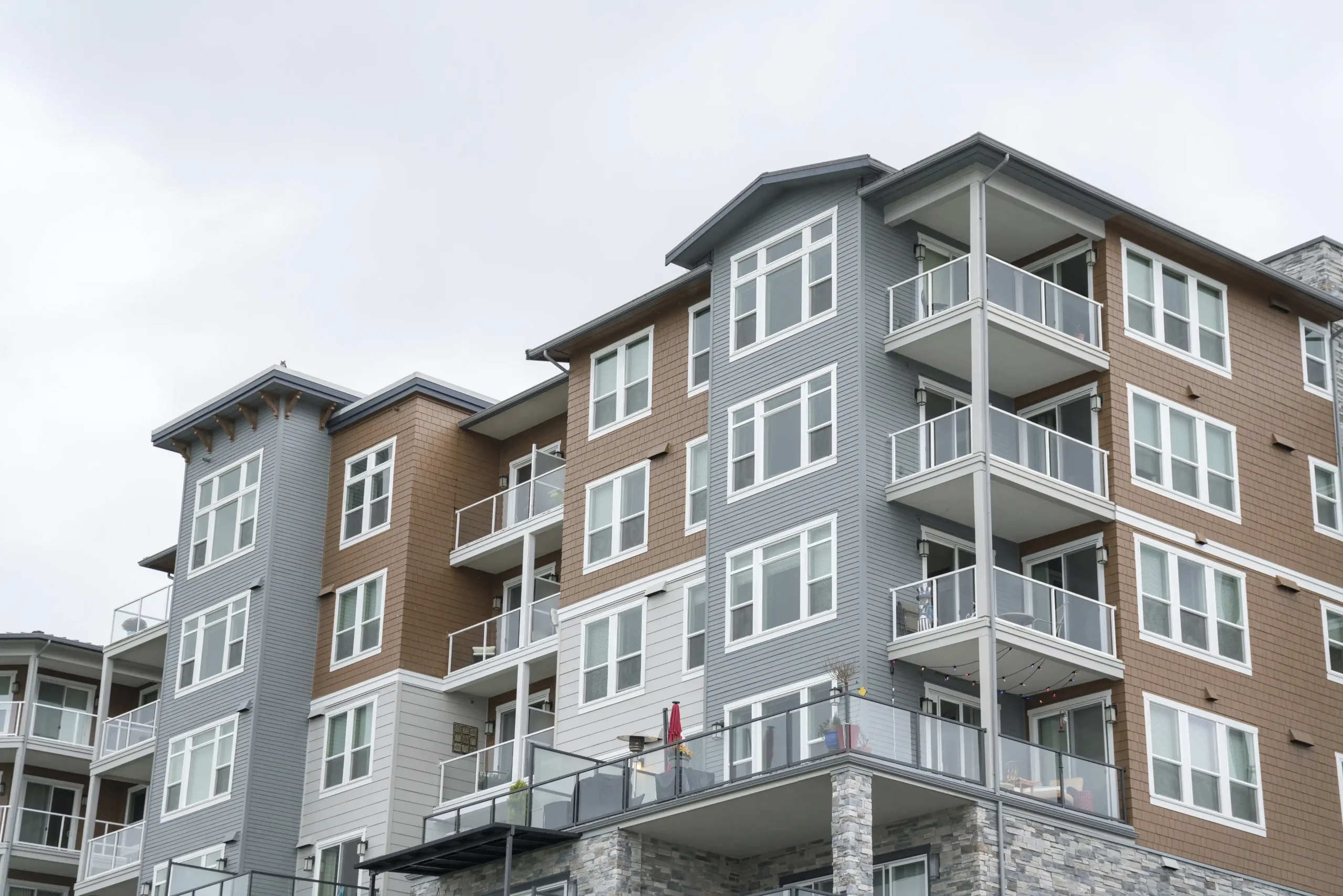 Multi-story residential building with gray, brown, and white exterior and glass balconies