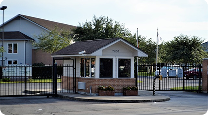Brick security checkpoint with metal gate and flower planters in residential complex