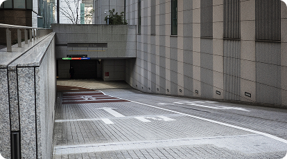Urban driveway leading to underground garage with directional arrows and signage