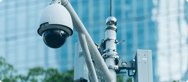Dome-style security camera mounted on a pole with control box in city setting